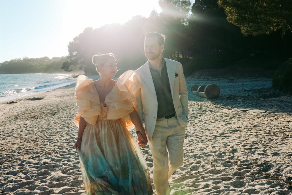 married couple hold hands on the beach